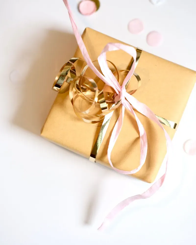 Gold gift box tied with pink ribbon