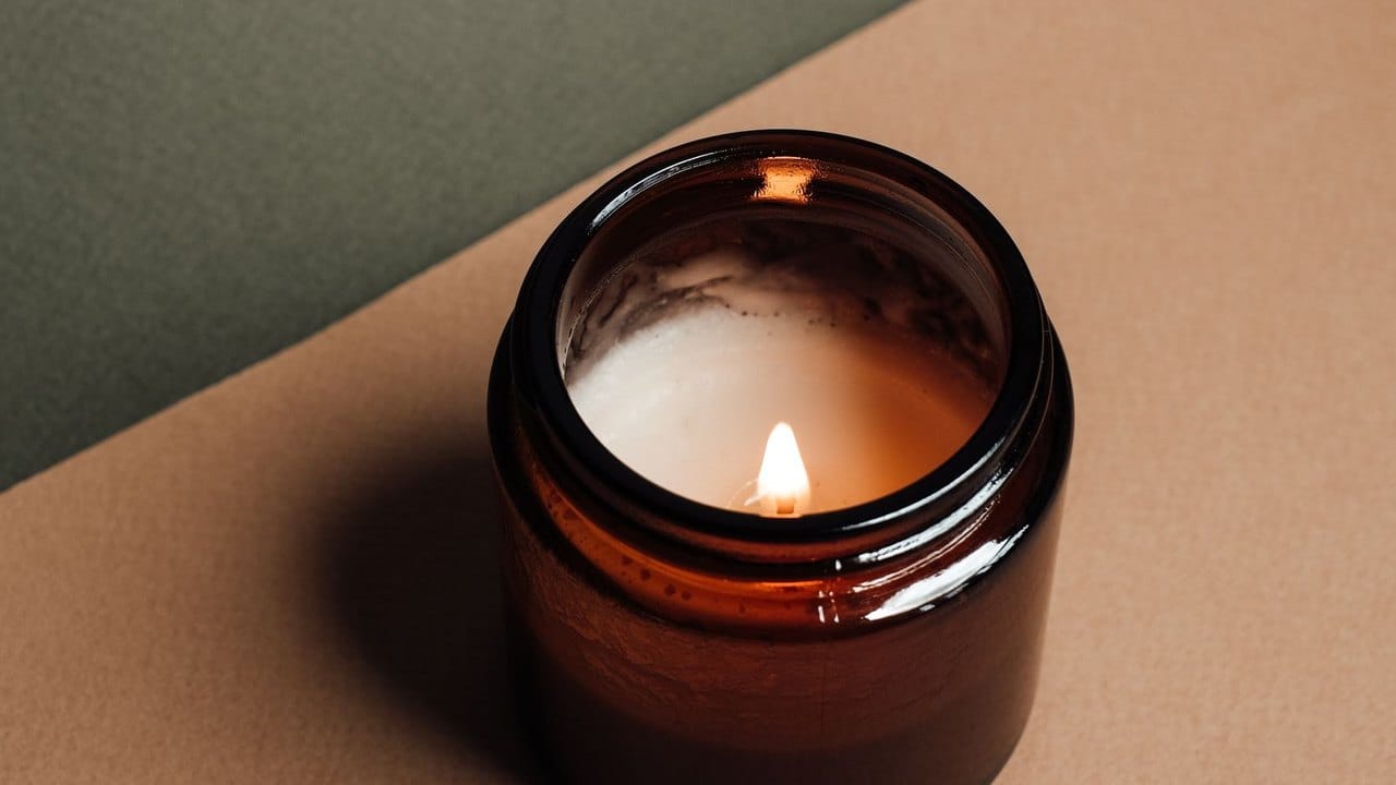 Lit candle in an amber glass jar