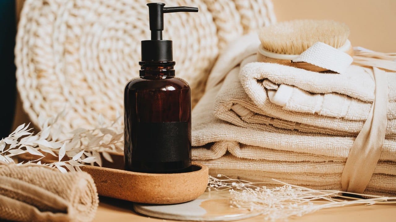 Amber pump bottle of oil beside folded cream towels