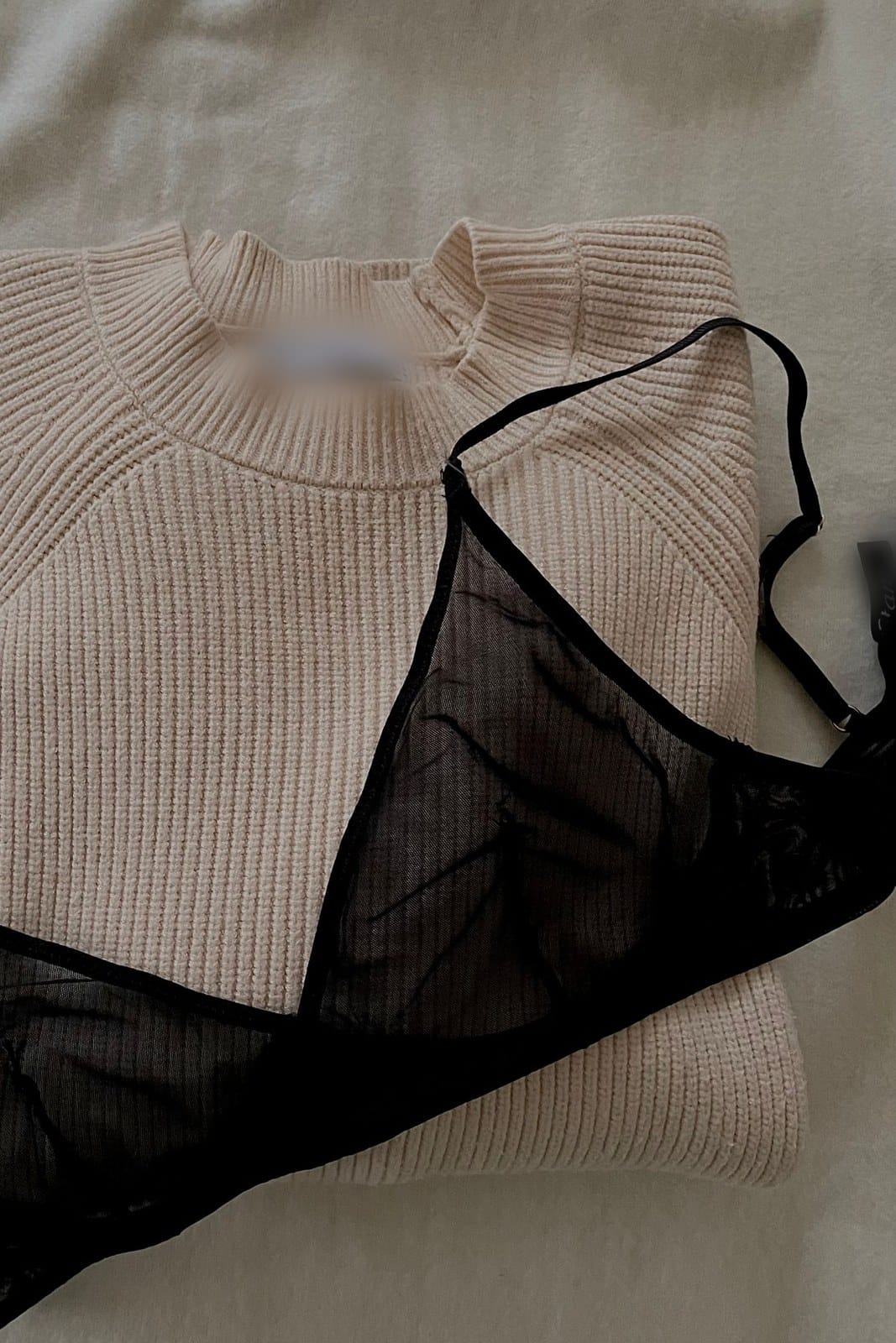 Black mesh bralette laid over a cream ribbed jumper